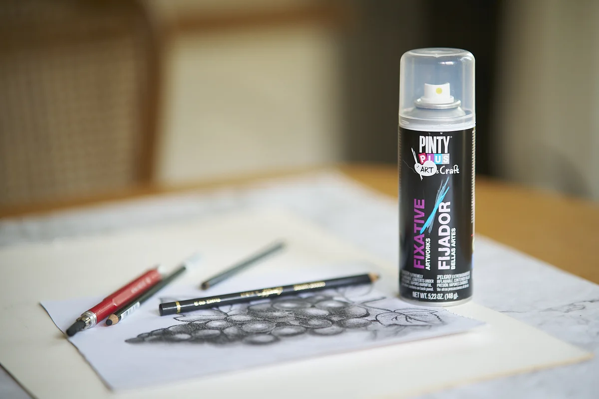 Pencil drawing of a bunch of grapes next to a can of Pintyplus Fixative and three pencils