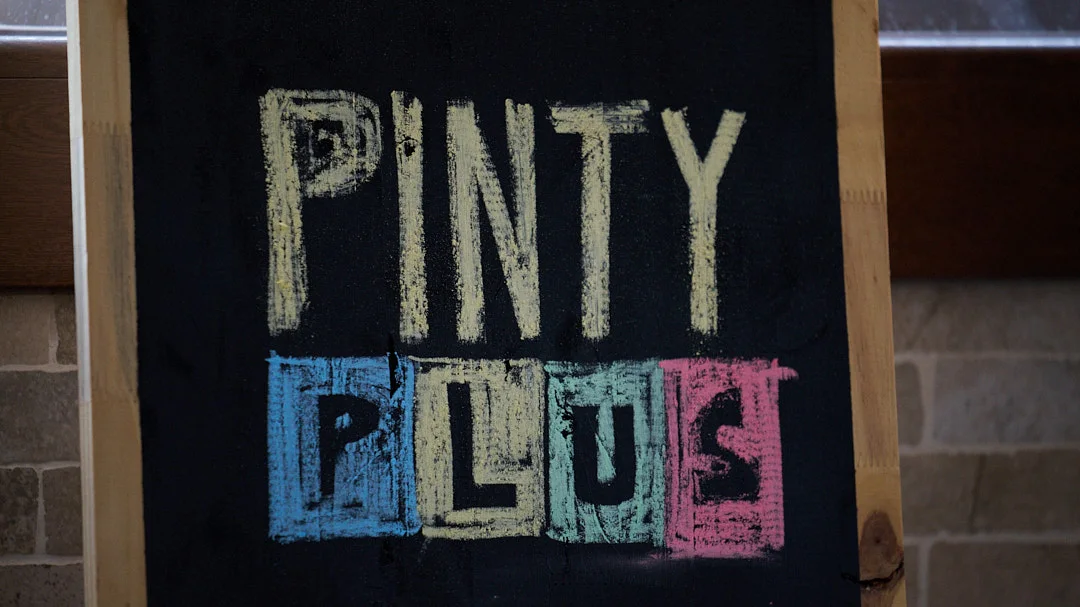 Blackboard with the words Pinty Plus drawn in coloured chalk