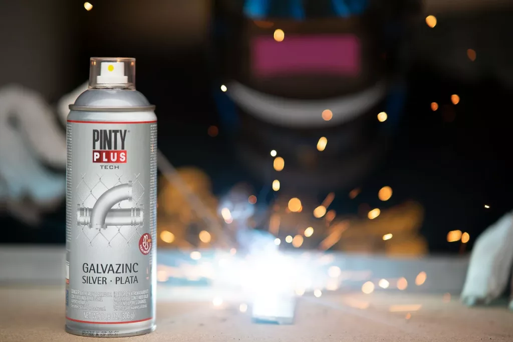 Pintyplus Galvazinc Silver spray can on a workbench while a welder works behind it